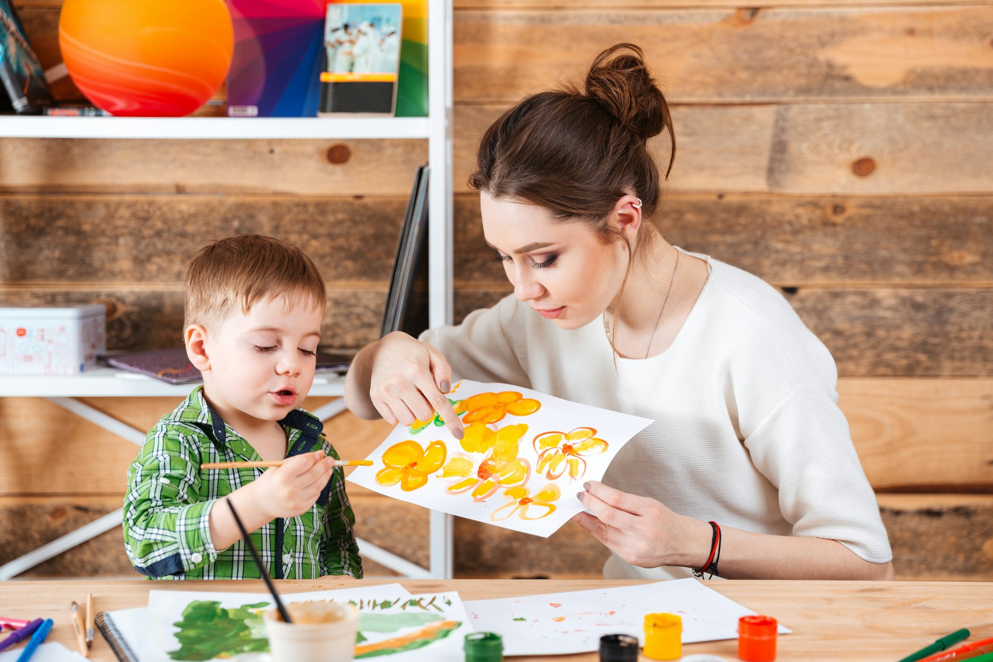 Mother teaching her little son painting in art school