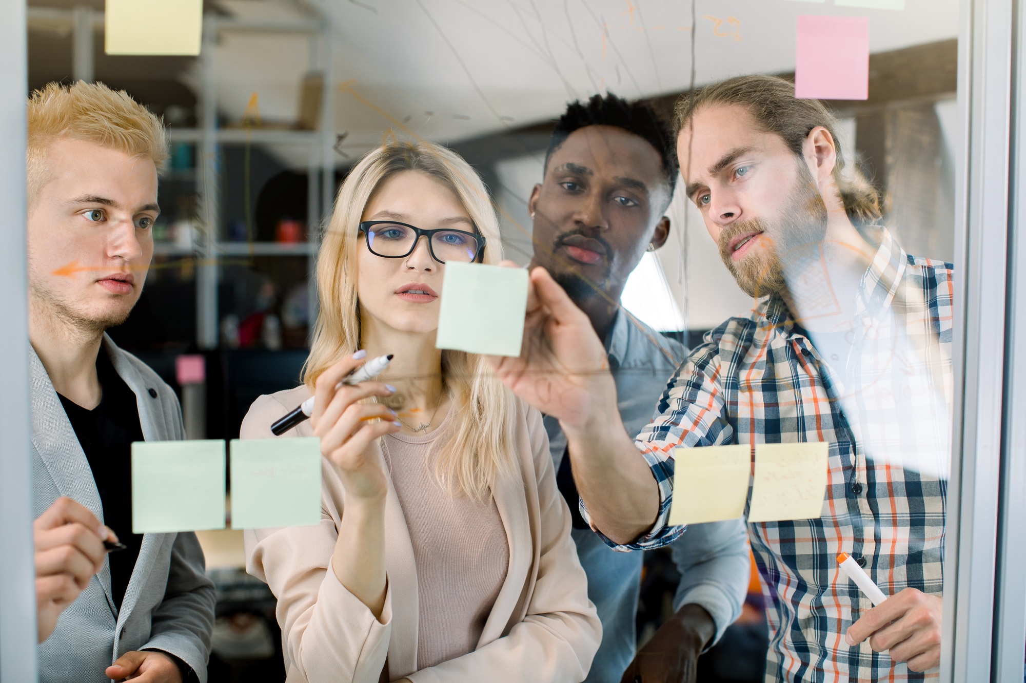 Focused blond Caucasian business woman mentor coach leader writing idea or chart on sticky notes on